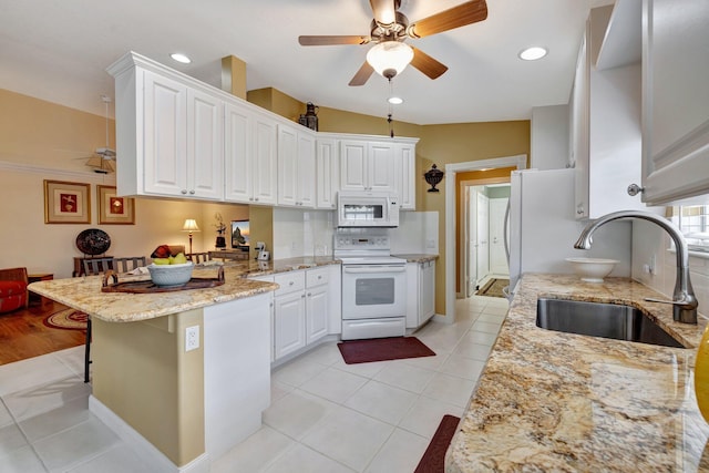 kitchen featuring a sink, a ceiling fan, white cabinetry, a peninsula, and white appliances