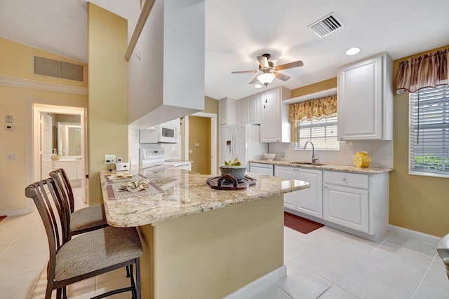 kitchen featuring white appliances, visible vents, a sink, and a peninsula