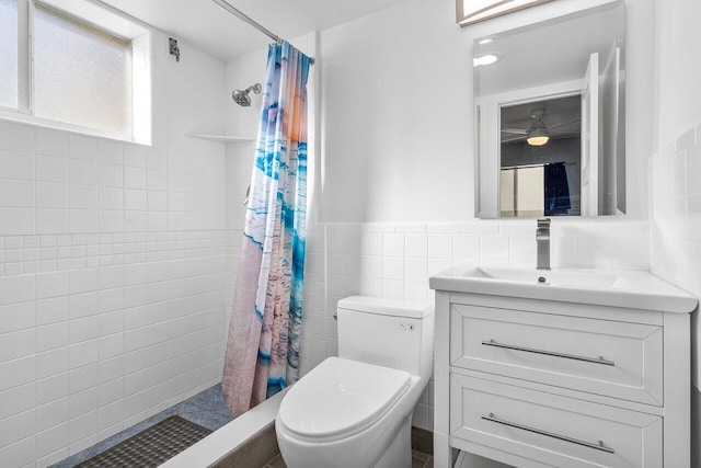 bathroom featuring tile walls, a wainscoted wall, toilet, tiled shower, and vanity