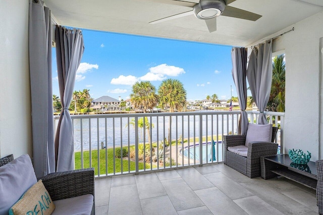 balcony with ceiling fan and a water view