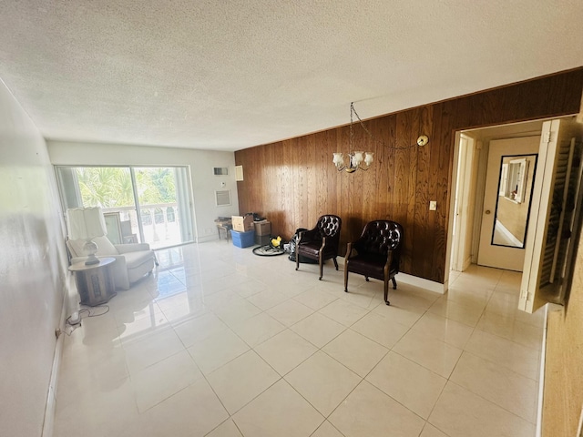 sitting room featuring wooden walls, visible vents, light tile patterned flooring, a notable chandelier, and a textured ceiling