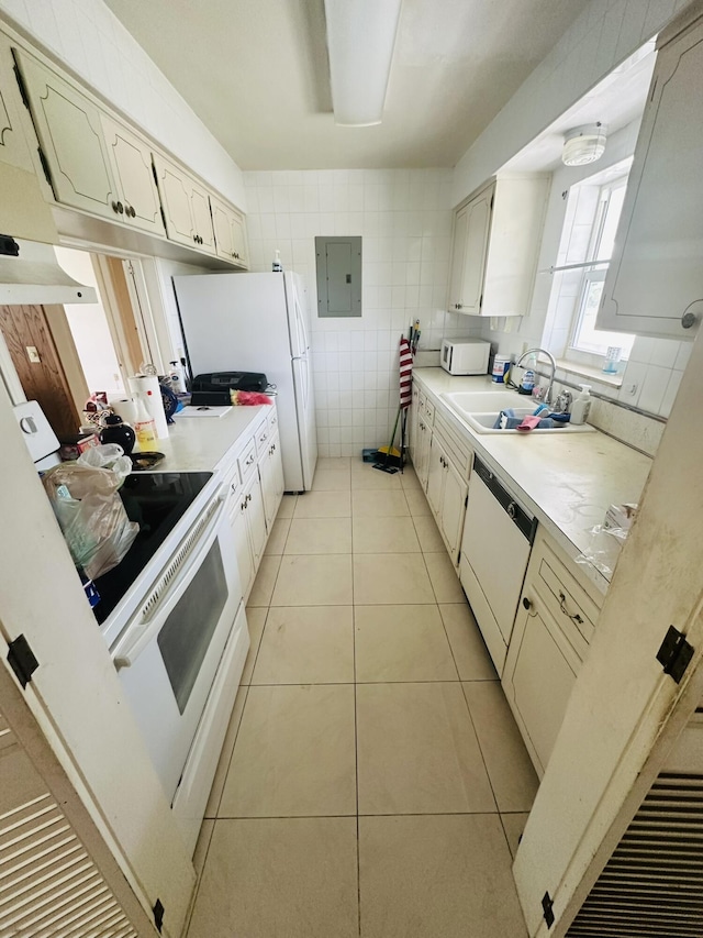 kitchen featuring light countertops, light tile patterned floors, white appliances, tile walls, and a sink