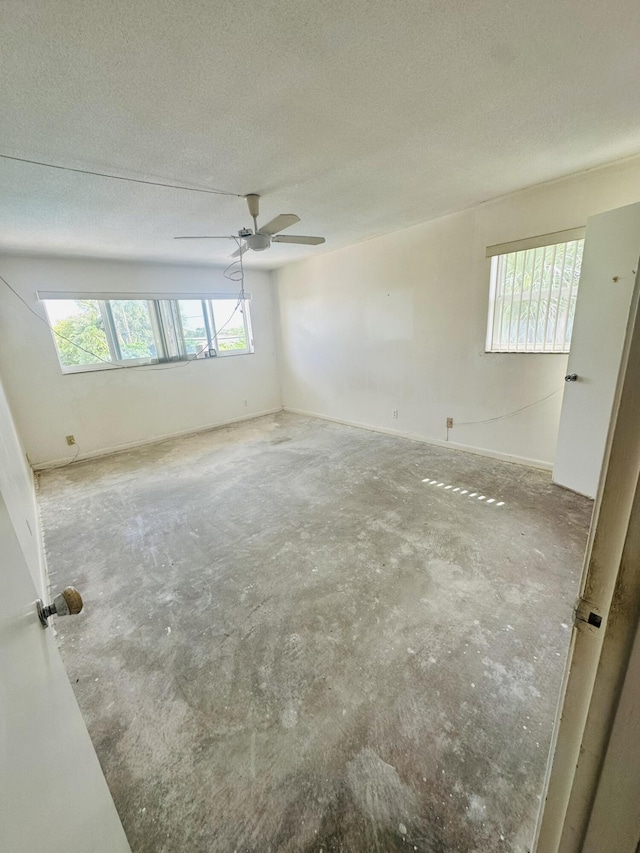 unfurnished room featuring ceiling fan, plenty of natural light, unfinished concrete flooring, and a textured ceiling