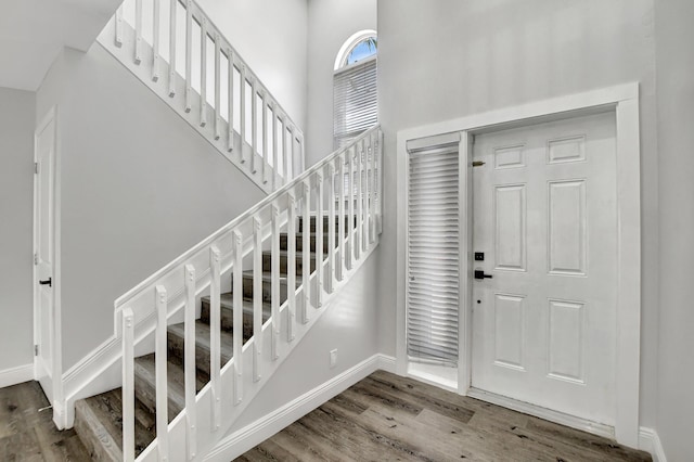 entrance foyer with stairway, a high ceiling, wood finished floors, and baseboards