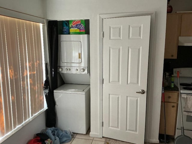 laundry area with light tile patterned floors, stacked washer and clothes dryer, and laundry area