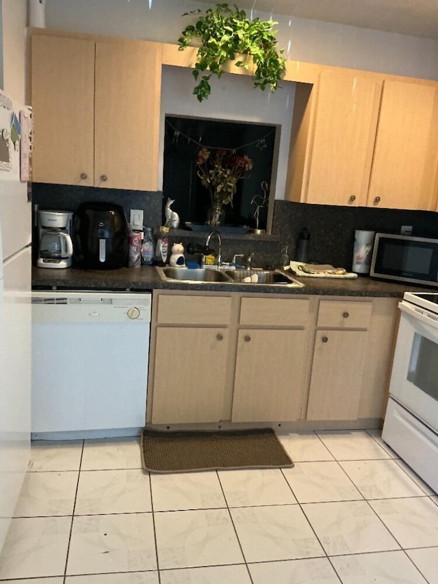 kitchen with white appliances, light tile patterned floors, a sink, dark countertops, and tasteful backsplash