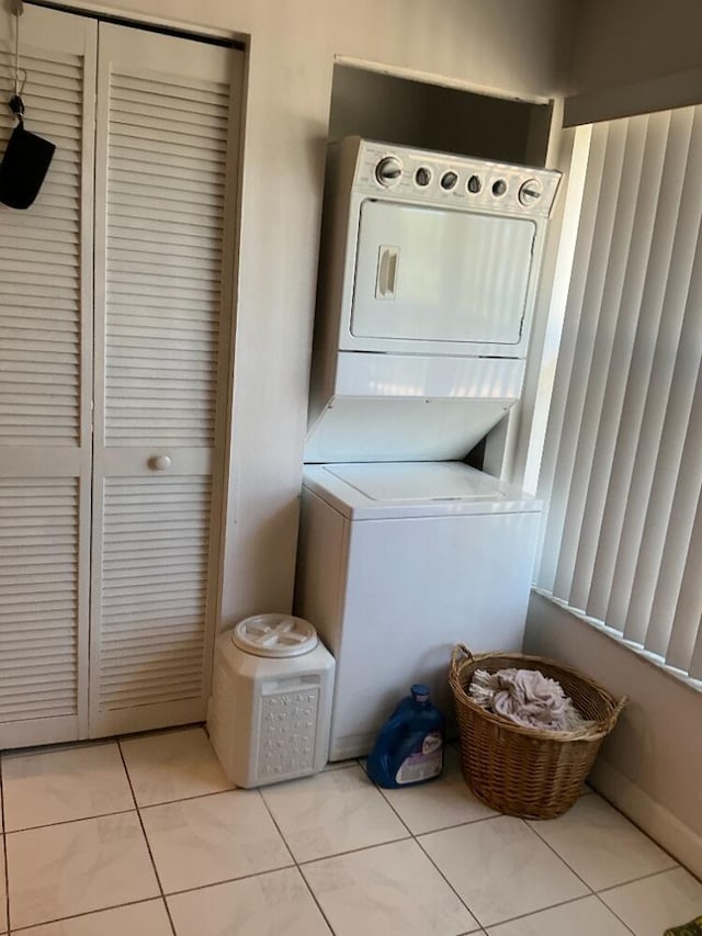 laundry room with stacked washer / drying machine, light tile patterned flooring, and laundry area