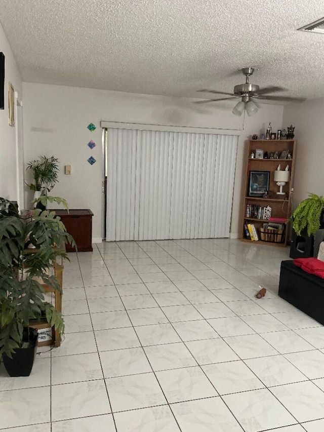 living area with light tile patterned floors, visible vents, a textured ceiling, and a ceiling fan