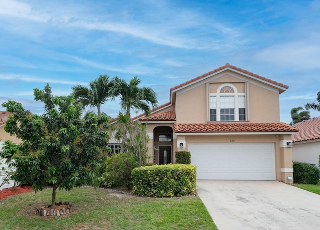 mediterranean / spanish home with a tiled roof, a garage, driveway, and stucco siding