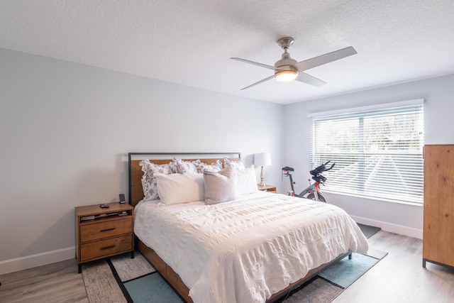 bedroom with baseboards, light wood finished floors, and a textured ceiling