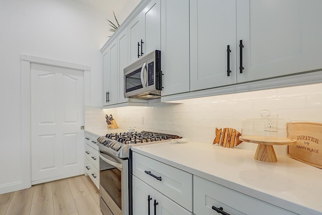 kitchen featuring light wood-style flooring, backsplash, and stainless steel appliances