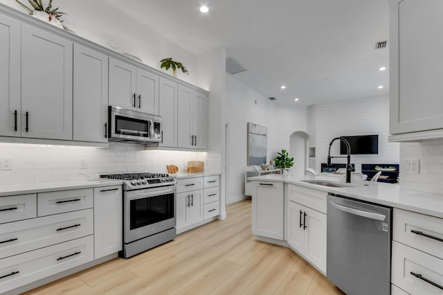 kitchen with visible vents, a sink, stainless steel appliances, light wood finished floors, and light countertops