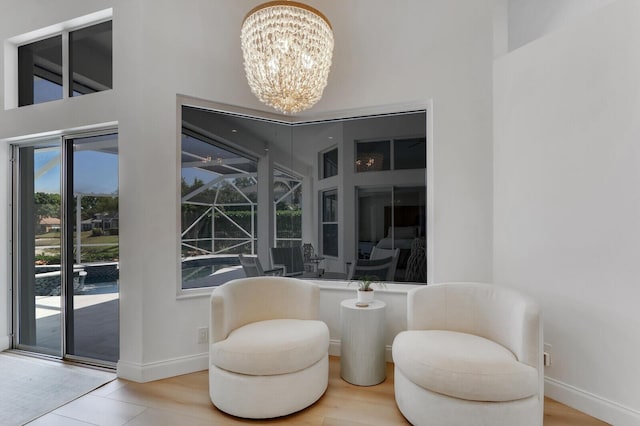 living area with a chandelier, a high ceiling, and baseboards