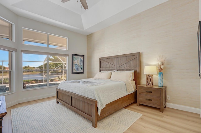 bedroom with baseboards, light wood-type flooring, a water view, and ceiling fan