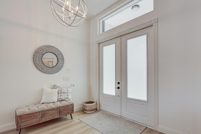 entrance foyer with light wood-type flooring, baseboards, a healthy amount of sunlight, and a chandelier