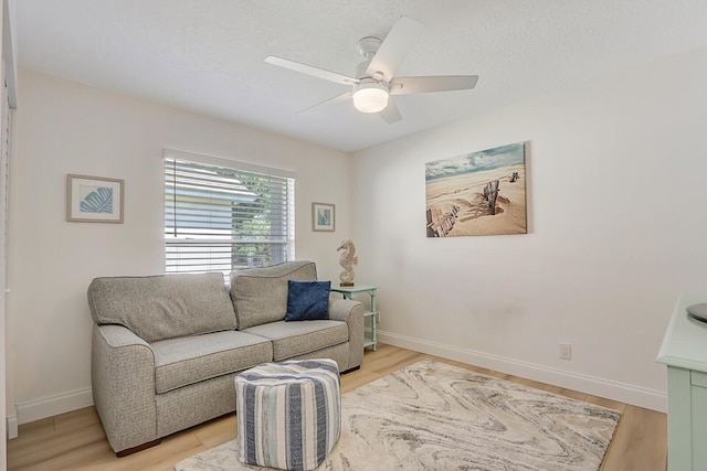 living area featuring light wood-style floors, baseboards, and ceiling fan