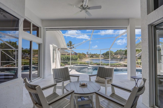 sunroom featuring a wealth of natural light, a ceiling fan, and a water view