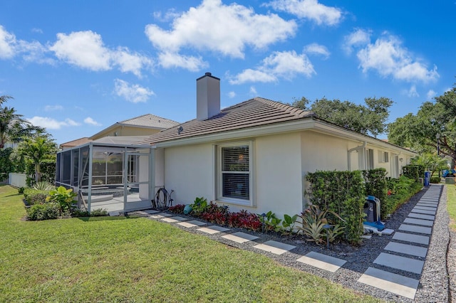 exterior space with a lanai, a tiled roof, stucco siding, a chimney, and a yard