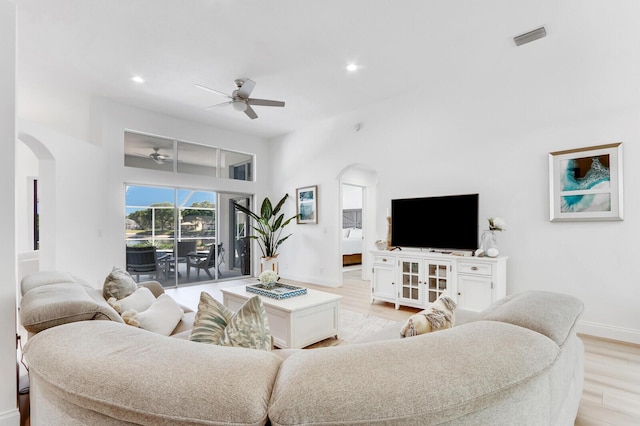 living area featuring a ceiling fan, visible vents, light wood finished floors, recessed lighting, and arched walkways