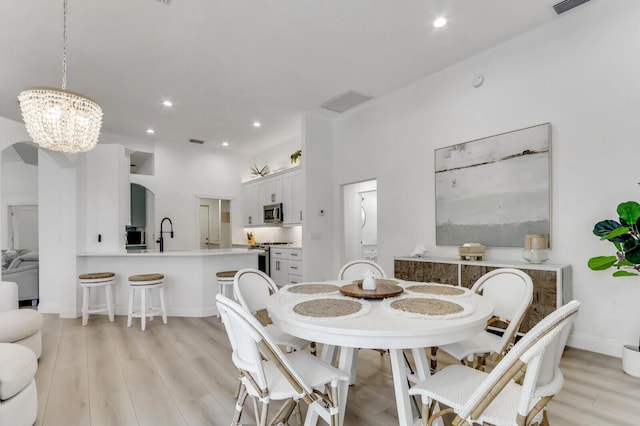 dining room with a notable chandelier, recessed lighting, light wood-type flooring, and baseboards