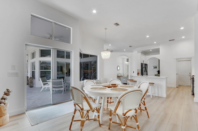 dining area with visible vents, baseboards, light wood-style flooring, recessed lighting, and arched walkways