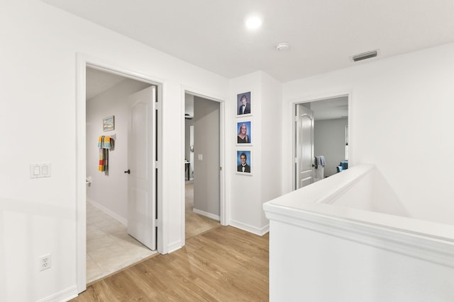 corridor featuring visible vents, light wood-style flooring, and baseboards