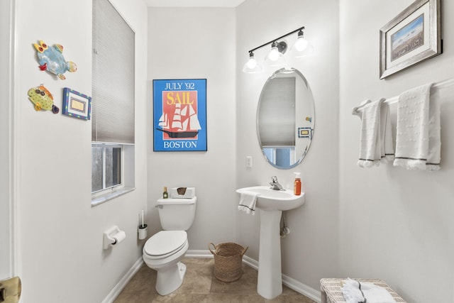 half bath featuring tile patterned flooring, toilet, and baseboards