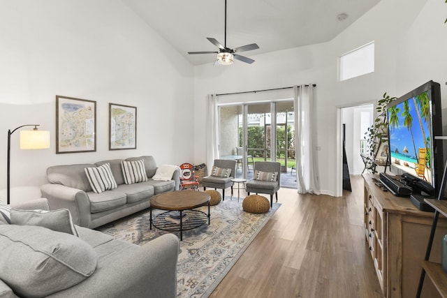 living room with baseboards, high vaulted ceiling, ceiling fan, and wood finished floors