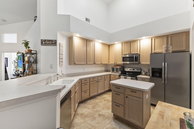 kitchen featuring visible vents, light countertops, a towering ceiling, stainless steel appliances, and a sink