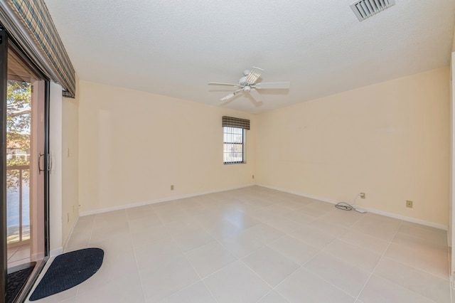 spare room featuring baseboards, a ceiling fan, visible vents, and a textured ceiling