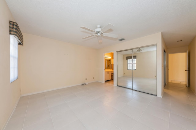 unfurnished bedroom featuring light tile patterned floors, baseboards, visible vents, a closet, and a textured ceiling