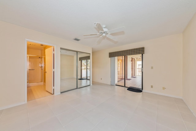 empty room with light tile patterned floors, a ceiling fan, baseboards, visible vents, and a textured ceiling