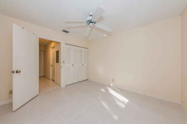 unfurnished bedroom with visible vents, electric panel, a textured ceiling, light tile patterned floors, and ceiling fan