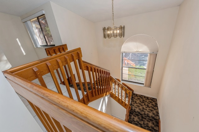 staircase with a notable chandelier