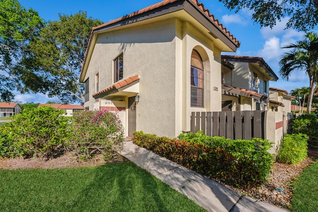 view of side of home with stucco siding and a tiled roof