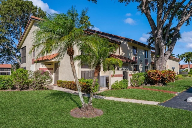 view of front of home with stucco siding, a tile roof, and a front lawn