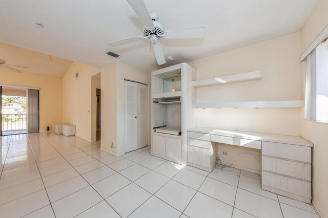 interior space featuring light tile patterned flooring, a ceiling fan, visible vents, and built in study area