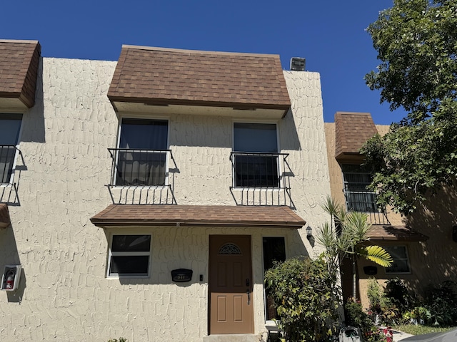 townhome / multi-family property with mansard roof and a shingled roof