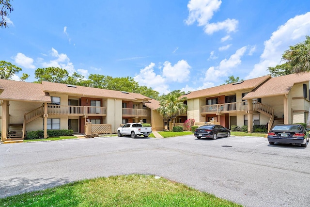 view of property with a residential view, uncovered parking, and stairs