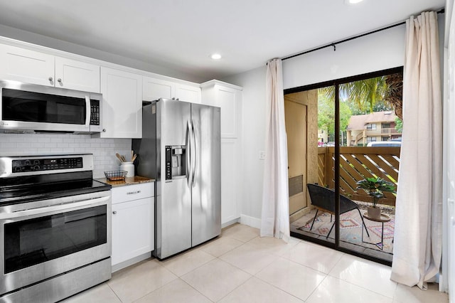 kitchen with decorative backsplash, light tile patterned floors, white cabinetry, and stainless steel appliances