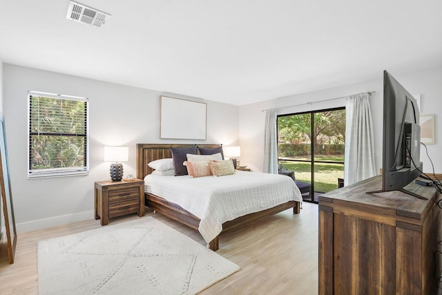 bedroom featuring visible vents, multiple windows, light wood-style floors, and access to outside