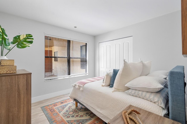 bedroom featuring a closet, light wood-type flooring, and baseboards