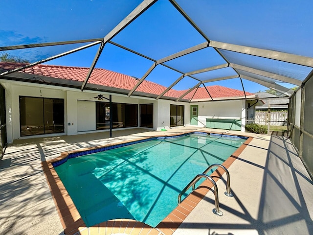 pool featuring glass enclosure, a ceiling fan, and a patio area