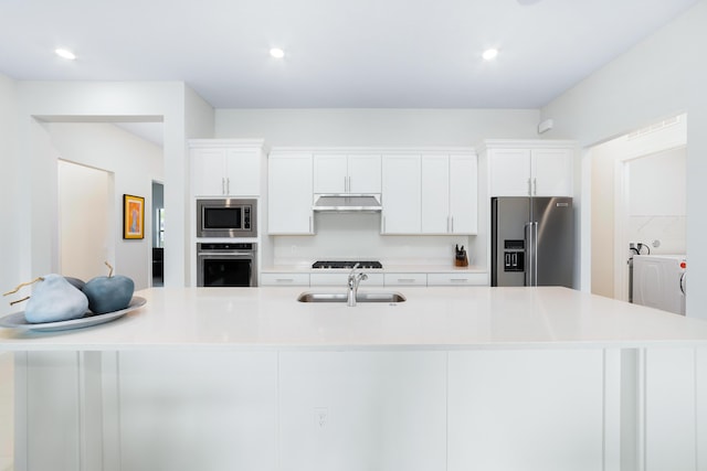 kitchen featuring under cabinet range hood, appliances with stainless steel finishes, white cabinets, and a sink