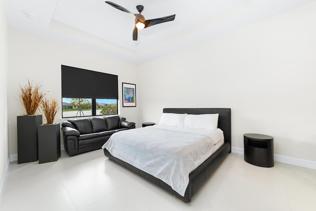 bedroom featuring tile patterned floors, ceiling fan, a raised ceiling, and baseboards