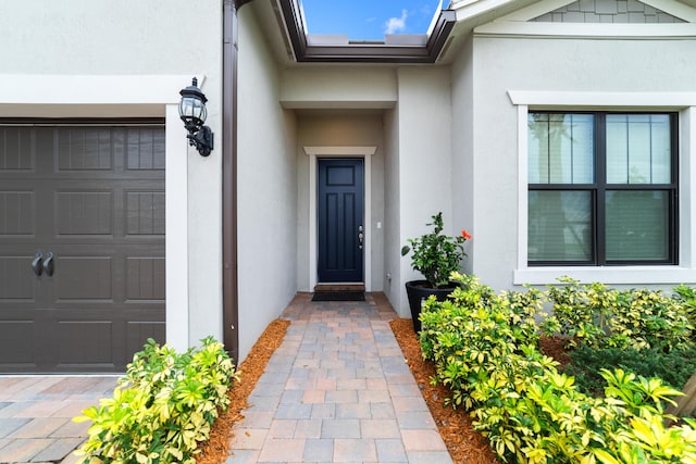 entrance to property featuring a garage and stucco siding