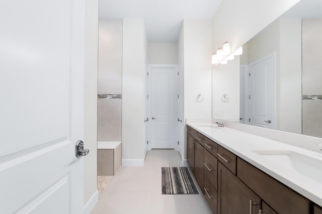 bathroom featuring double vanity, tile patterned flooring, baseboards, and a sink