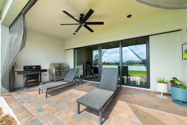 view of patio with glass enclosure, exterior kitchen, area for grilling, and ceiling fan