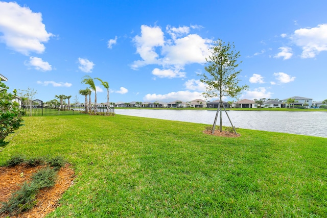 view of yard featuring fence, a water view, and a residential view