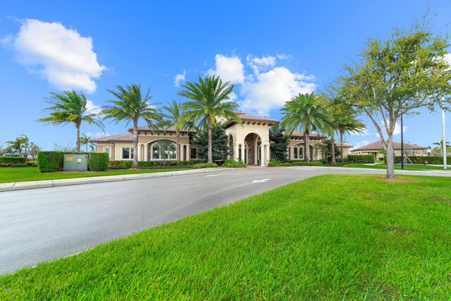 mediterranean / spanish-style home with a front lawn, a tile roof, and stucco siding